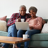 Couple sitting on a couch looking at a laptop
