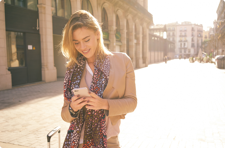 Young woman looking down at her phone while traveling abroad
