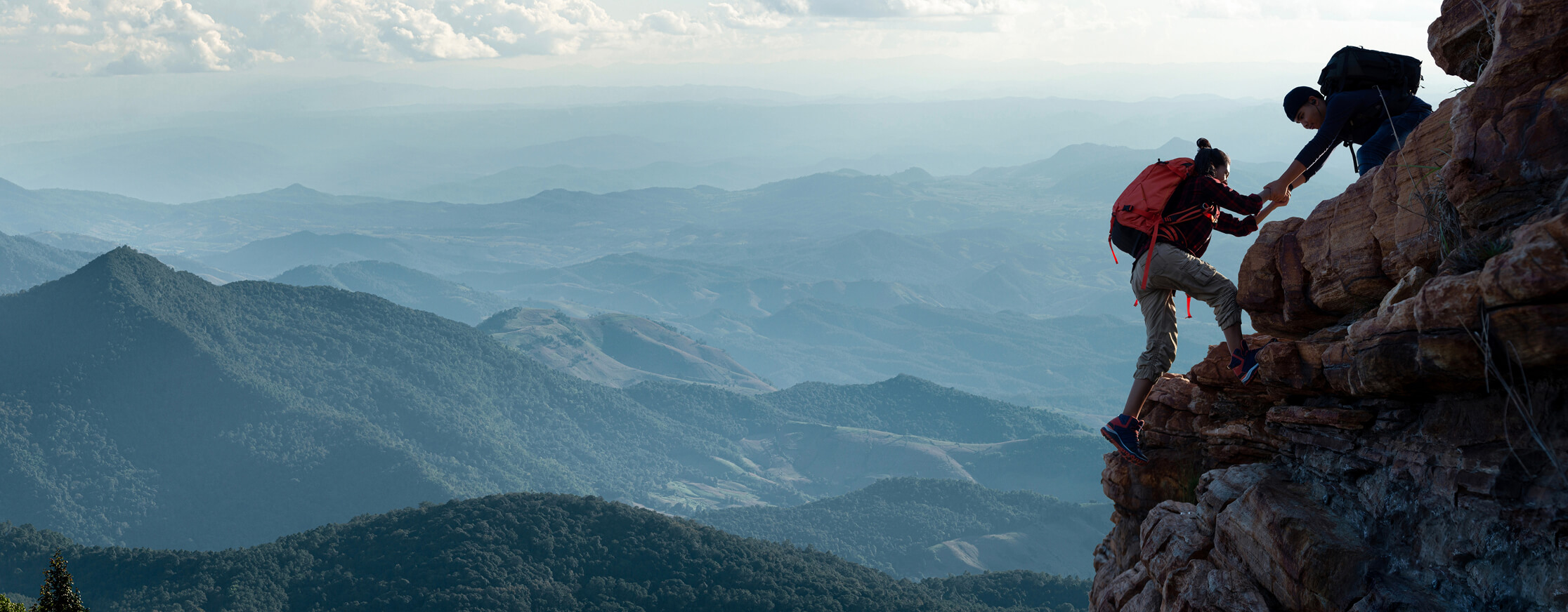 pair of people climbing cliff