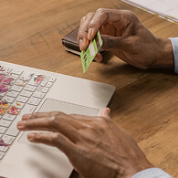 A laptop user has his credit card in hand and prepares to make an online payment